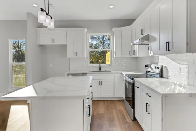 a kitchen with a sink a stove a refrigerator and white cabinets