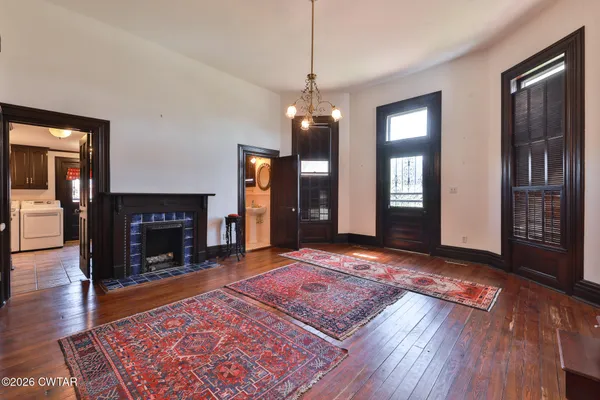a view of an empty room with wooden floor fireplace and a window