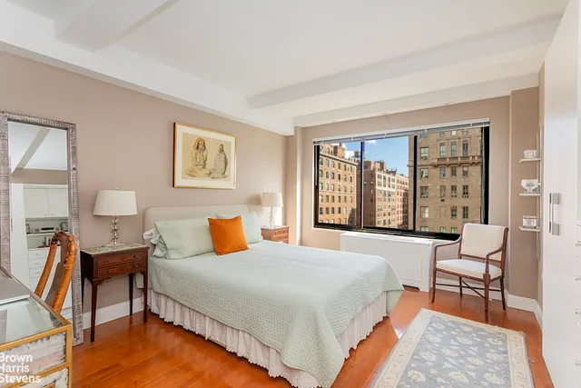 a bedroom with a bed a chair and next to a window