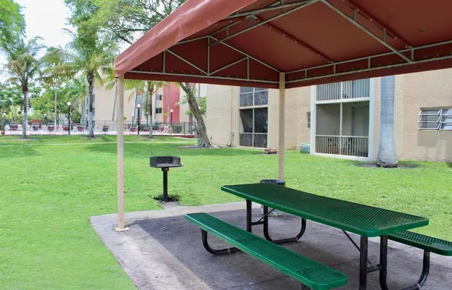 a view of a backyard with table and chairs potted plants and large tree