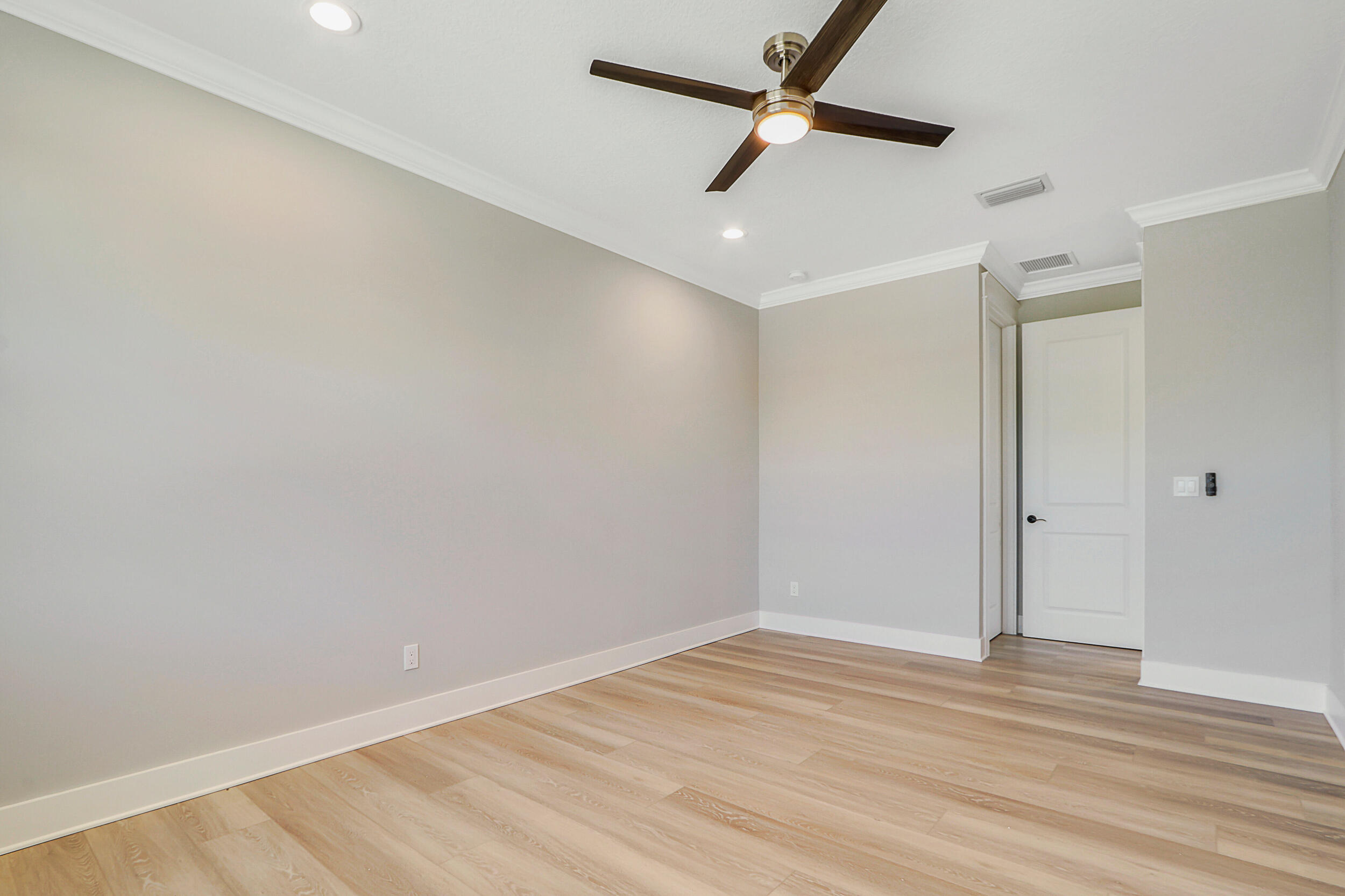 4629 Southeast Manatee Lane Stuart, FL 34997 - Photo 21 of 31 an empty room with wooden floor ceiling fan and windows