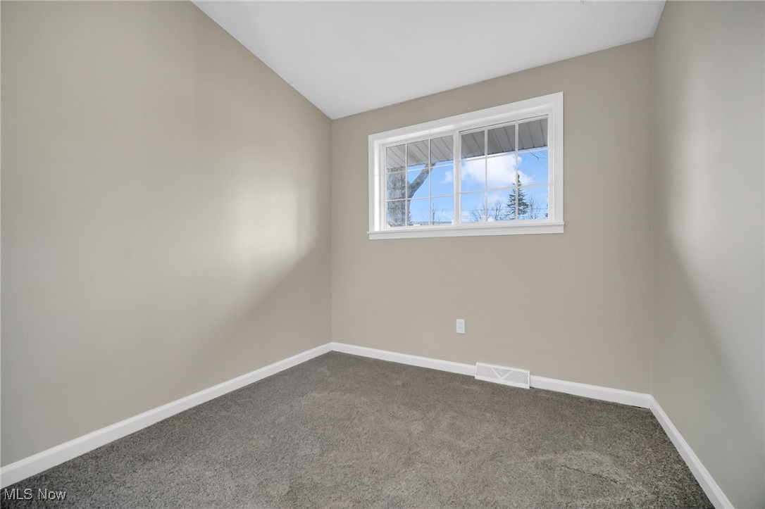 6320 Jaycox Road North Ridgeville, OH 44039 - Photo 25 of 34 Unfurnished room with visible vents, baseboards, dark carpet, and vaulted ceiling
