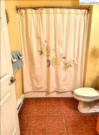 a bathroom with a toilet and shower curtain