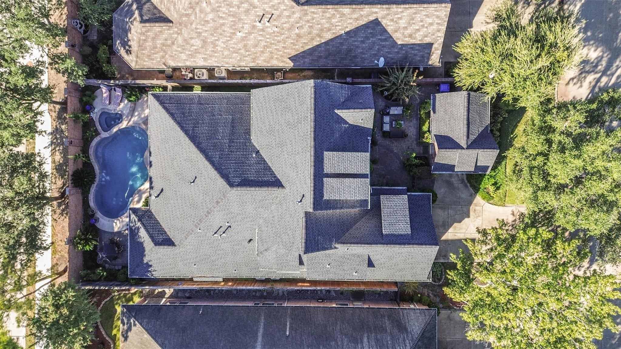 11413 Gallant Ridge Lane Houston, TX 77082 - Photo 10 of 50 This aerial view showcases a spacious property with a large roof and a uniquely shaped pool. It includes a driveway and lush greenery, providing a private and inviting outdoor space.