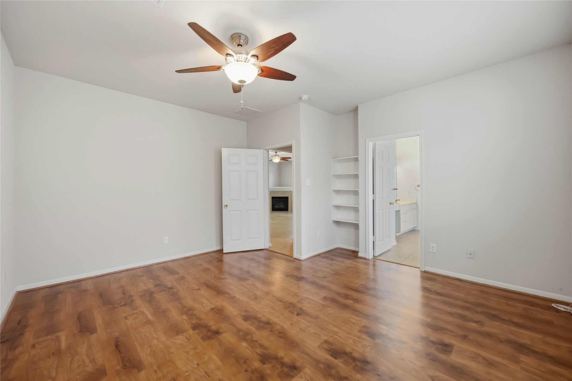 29526 Winton Wood Way Spring, TX 77386 - Photo 11 of 29 Spacious first-floor primary suite featuring an en suite bath, built-in shelving, and easy access to the main living area.