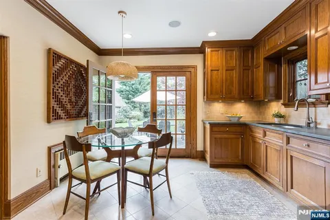 a dining hall with stainless steel appliances granite countertop a stove a sink a dining table and chairs with wooden floor