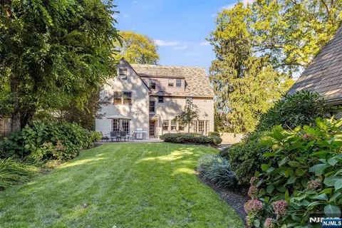 a view of a big house with a big yard and large trees