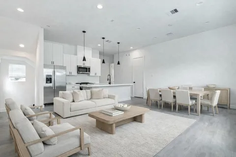 a living room with furniture white walls and kitchen view