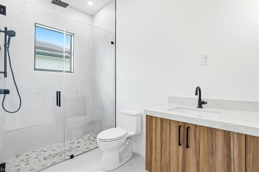 14318 Charthouse Circle Naples, FL 34114 - Photo 14 of 36 a bathroom with a granite countertop sink a toilet and shower