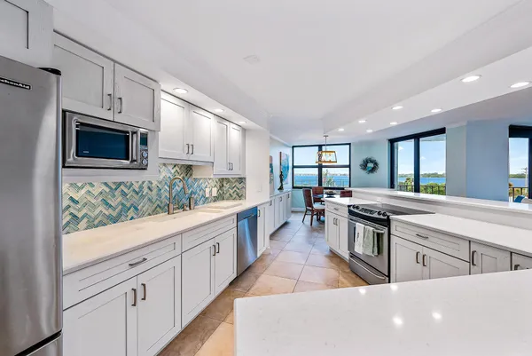 a large white kitchen with stainless steel appliances granite countertop lots of white cabinets a stove and a sink