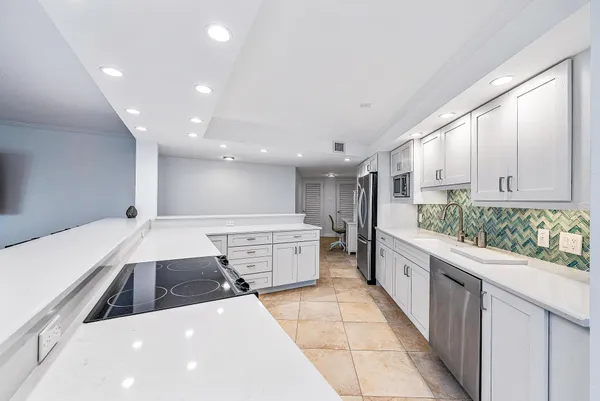 a large kitchen with stainless steel appliances a large counter top a stove and a refrigerator