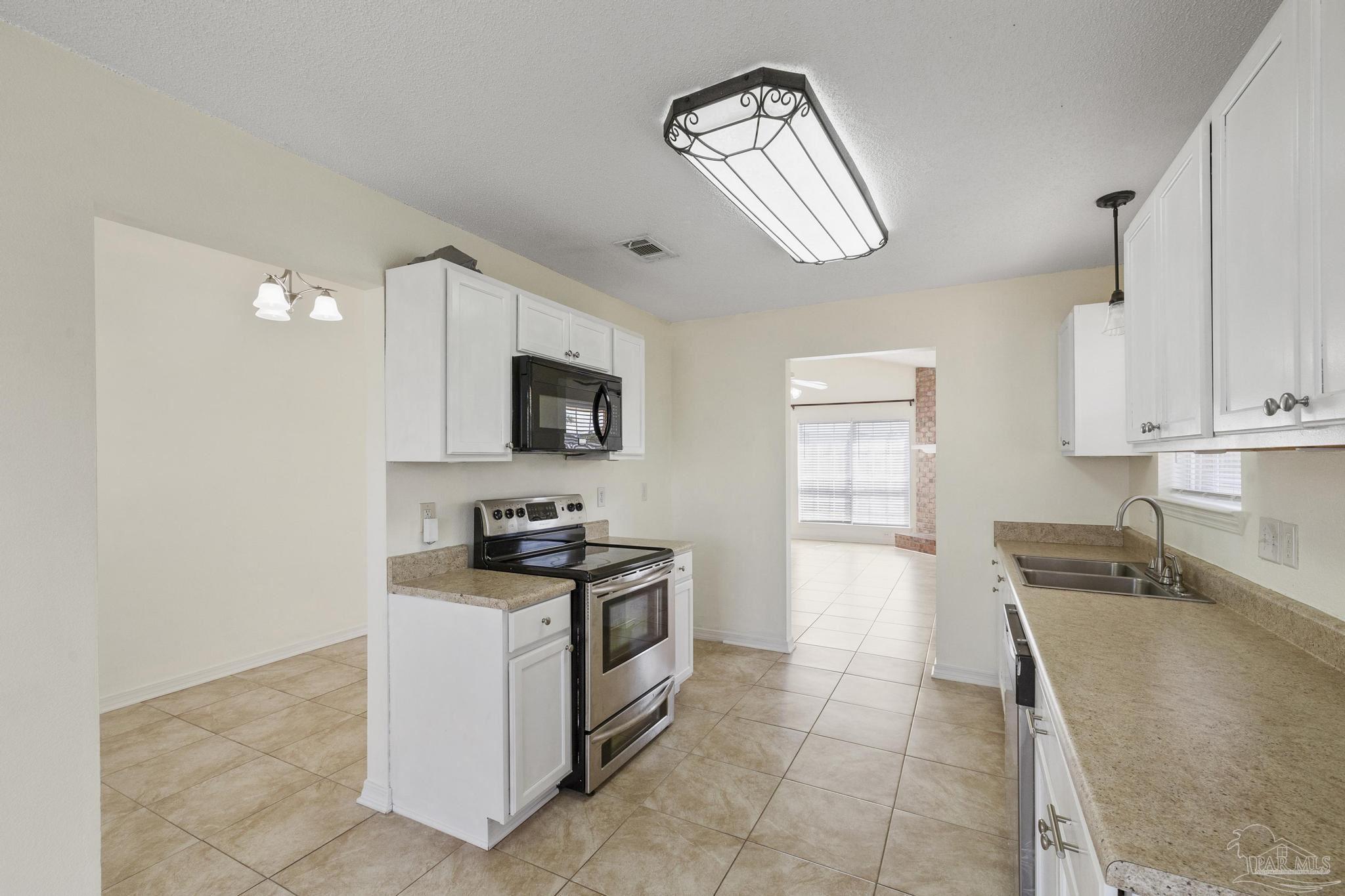 4769 Ribault Lane Milton, FL 32570 - Photo 14 of 34 a kitchen with granite countertop a sink a stove top oven and cabinetry