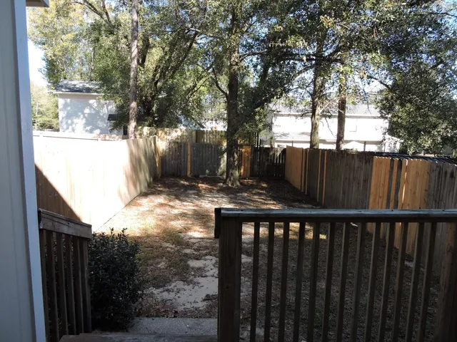 a view of backyard with wooden fence and trees