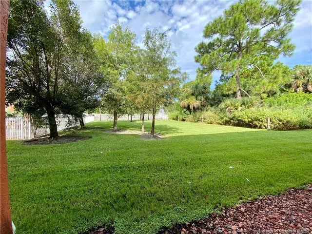 a view of grassy field with benches and trees all around