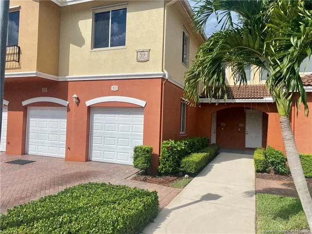 a front view of a house with garage and plants