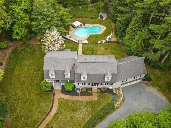an aerial view of a house with swimming pool and large trees