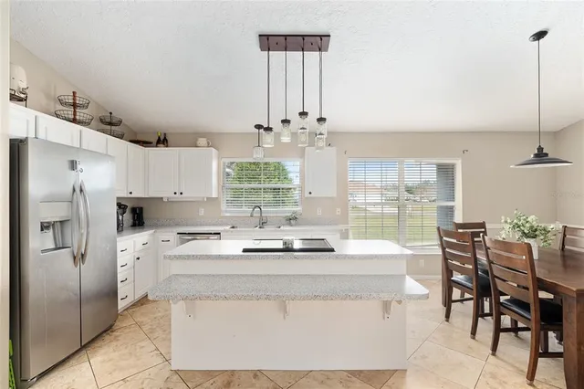 a kitchen with stainless steel appliances kitchen island granite countertop a table chairs and a refrigerator