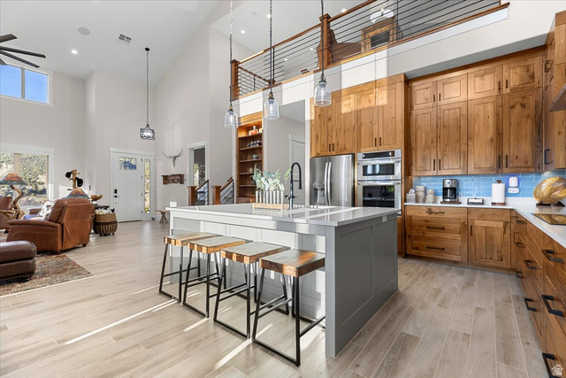 1210 East Bristle Cone Road Pine Valley, UT 84781 - Photo 12 of 54 Two-tone kitchen, a kitchen breakfast bar, a kitchen island with sink, decorative backsplash, and a high ceiling