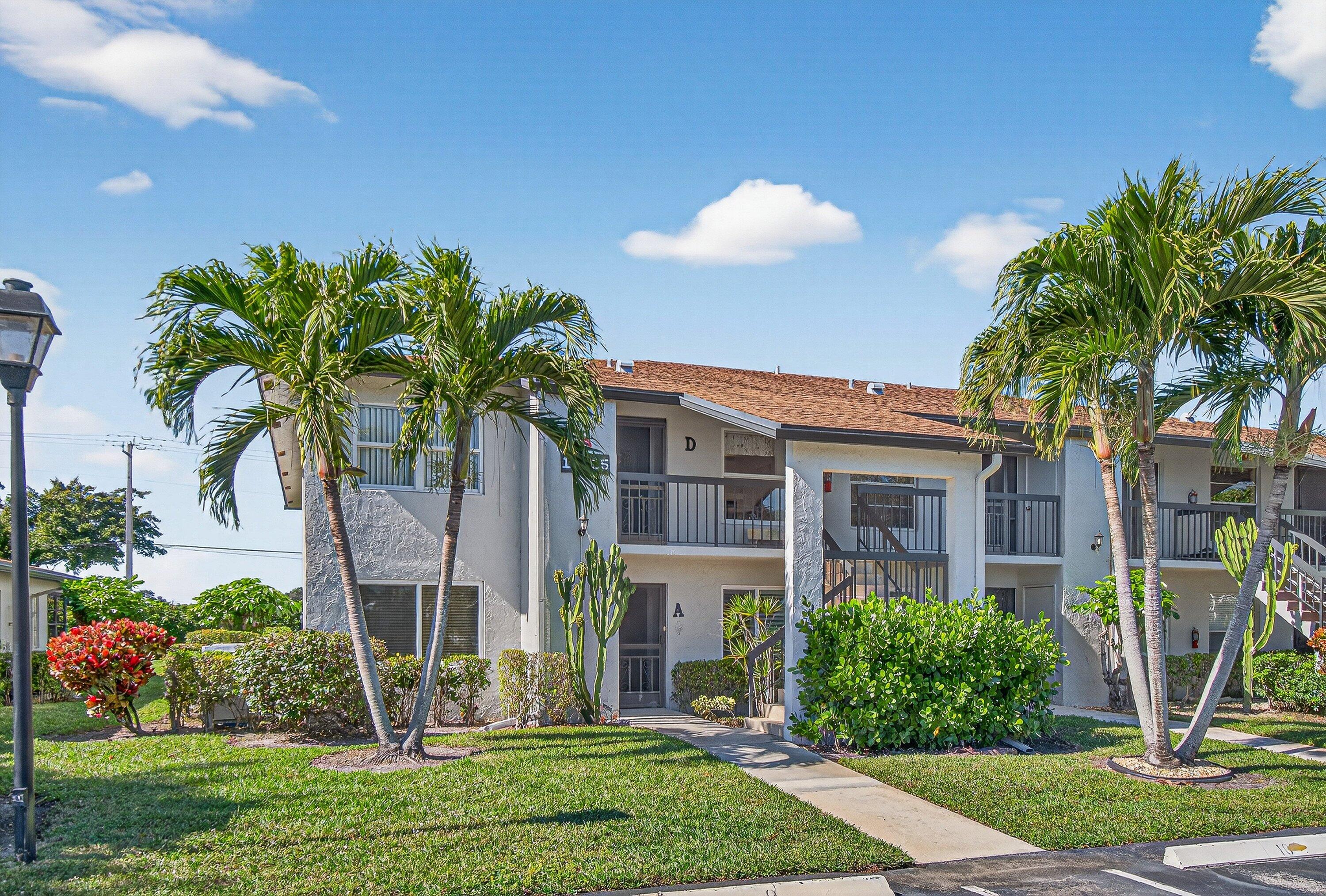 13465 Fishtail Palm Court, Unit D Delray Beach, FL 33484 - Photo 26 of 29 a front view of a house with a yard and potted plants