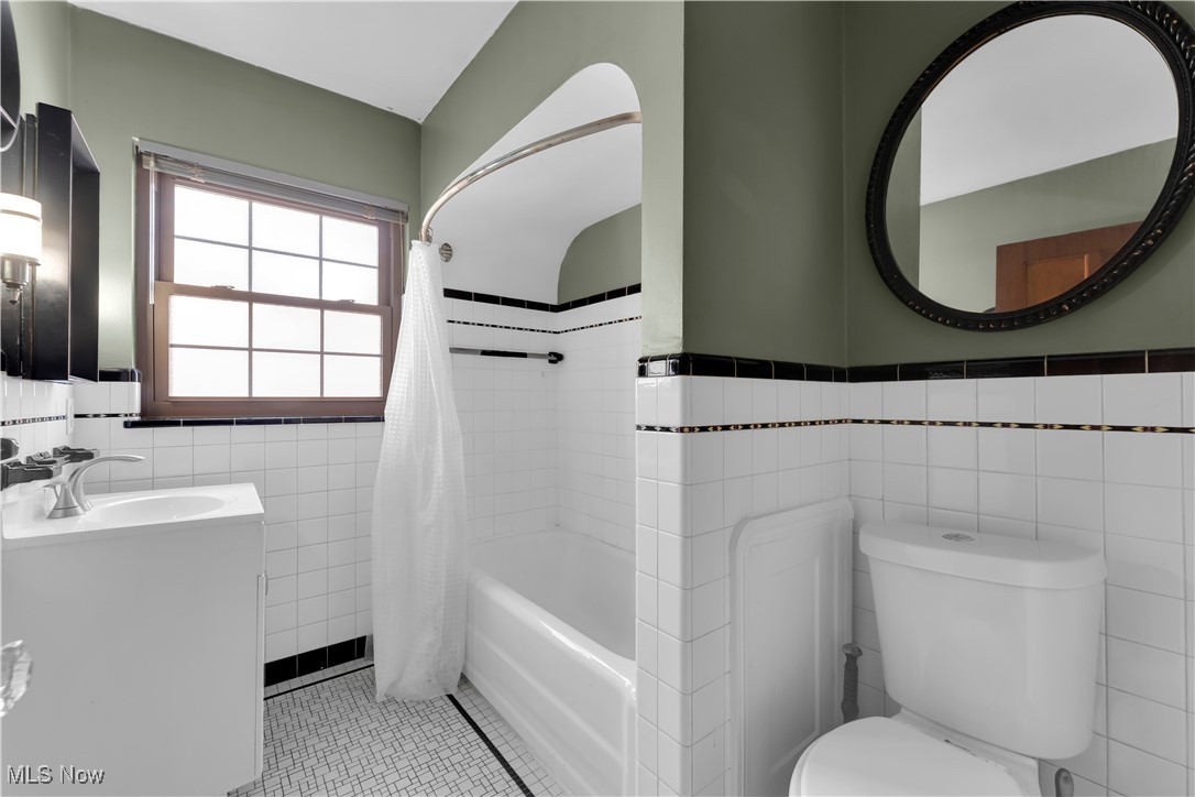 3739 Warren Road Cleveland, OH 44111 - Photo 15 of 40 Full bathroom with tile walls, shower / bath combo, a wainscoted wall, vanity, and light tile patterned flooring