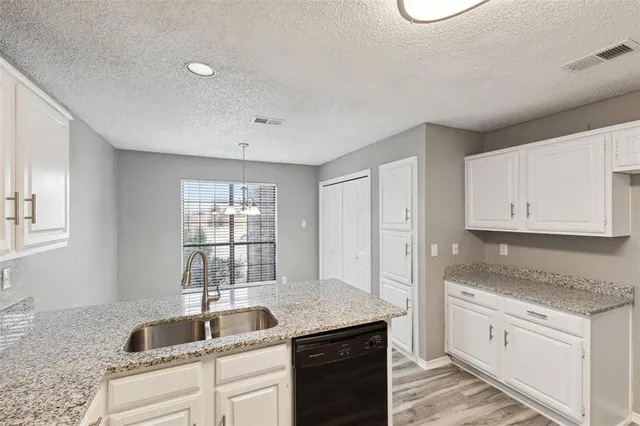 a kitchen with granite countertop white cabinets sink and window