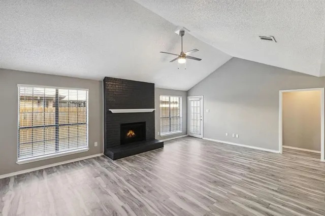 an empty room with windows fireplace and wooden floor