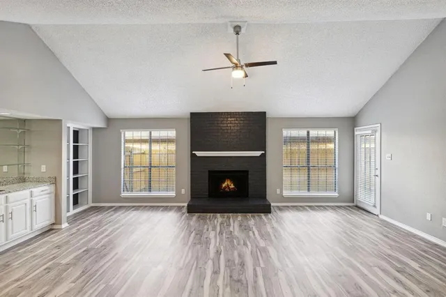 an empty room with windows fireplace and wooden floor