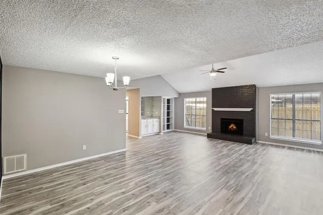 an empty room with wooden floor fireplace and windows