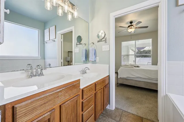 a en suite bathroom with a tub double vanity and window