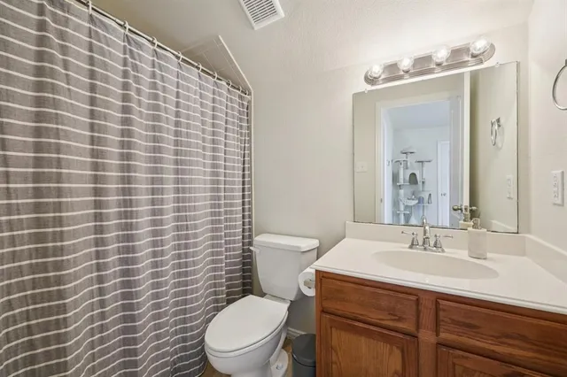 a bathroom with a granite countertop toilet a sink a mirror and a shower