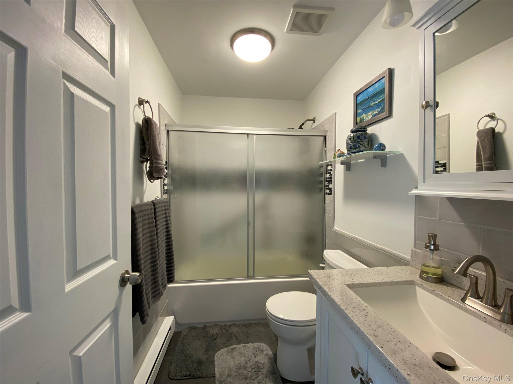 274 Berwick Court, Unit A Ridge, NY 11961 - Photo 18 of 31 Full bathroom featuring a baseboard heating unit, bath / shower combo with glass door, and vanity