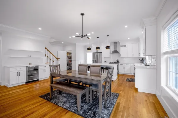 a large kitchen with stainless steel appliances granite countertop a sink dishwasher a stove and a dining table with wooden floor
