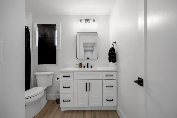 a bathroom with a toilet a sink a mirror a vanity and window
