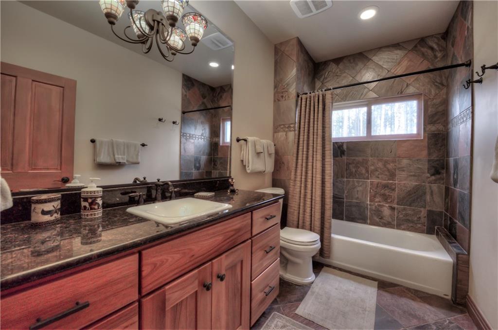 324 4 O'Clock Run Road Breckenridge, CO 80424 - Photo 17 of 25 a bathroom with a granite countertop sink a toilet a mirror a vanity and bathtub