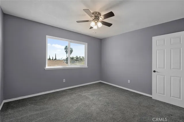 an empty room with windows and ceiling fan