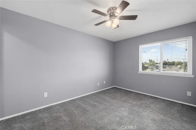 an empty room with a window and a fan
