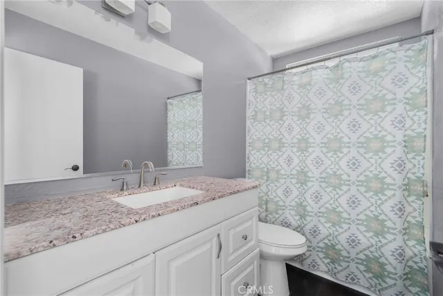 a bathroom with a granite countertop sink a toilet and a mirror