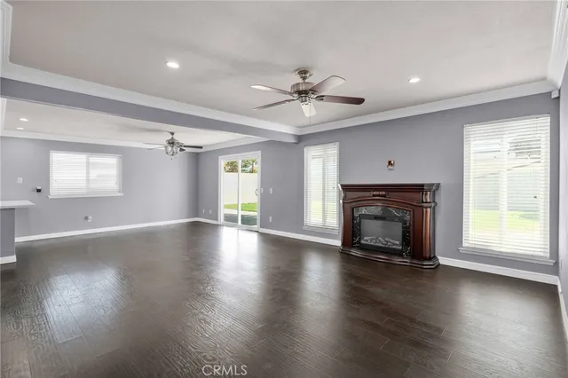 an empty room with wooden floor fireplace and windows