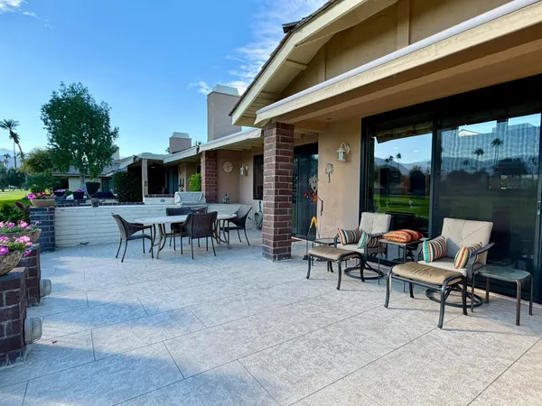 a view of a patio with table and chairs potted plants with floor to ceiling window and potted plants