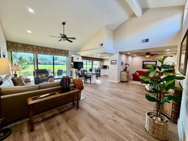 a living room with furniture potted plant floor to ceiling window and a table