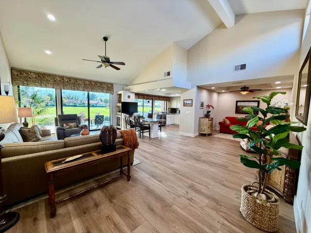 a living room with furniture potted plant floor to ceiling window and a table