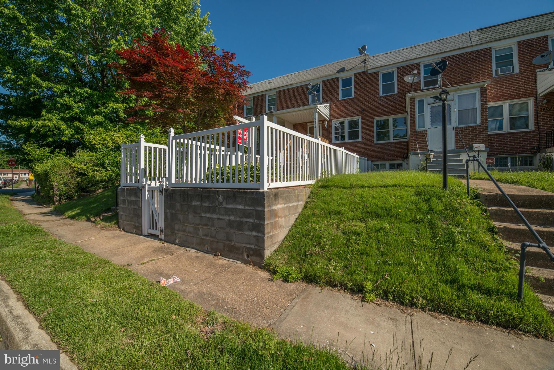 7404 Kirtley Road Baltimore, MD 21222 - Photo 13 of 13 a view of a brick house with a small yard and large trees