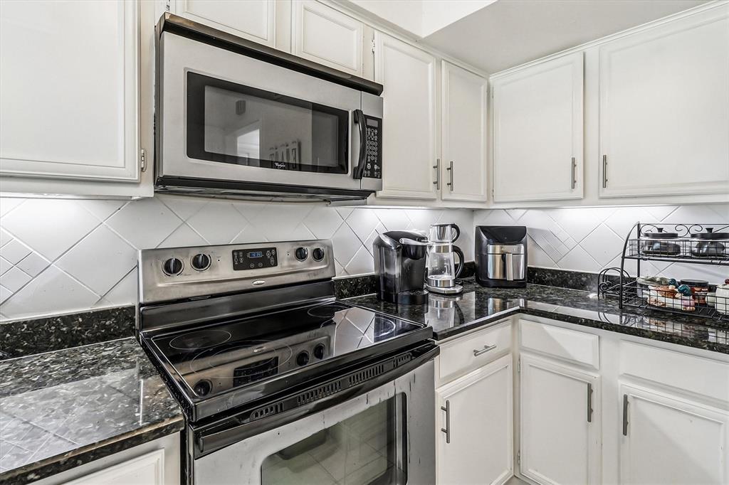 15151 Berry Trail, Unit 1307 Dallas, TX 75248 - Photo 11 of 27 Kitchen featuring appliances with stainless steel finishes, backsplash, white cabinets, and dark stone counters