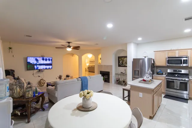 a kitchen with stainless steel appliances kitchen island granite countertop a table chairs and a refrigerator