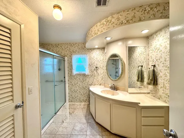 a bathroom with a granite countertop sink mirror and shower