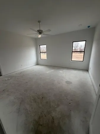 an empty room with windows and ceiling fan