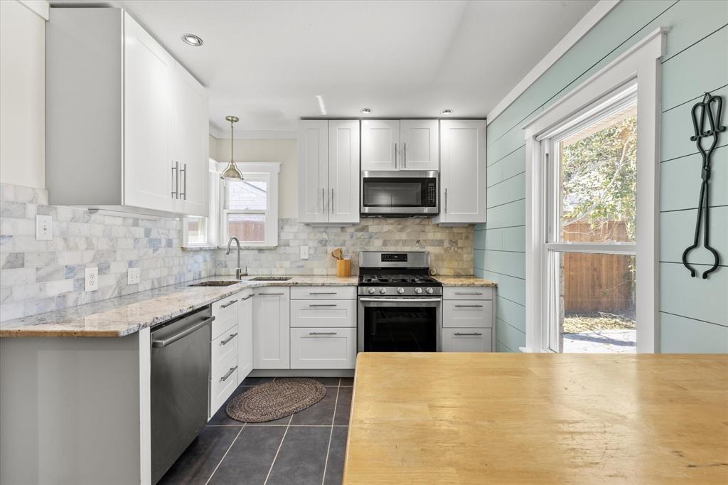 2919 Maple Springs Boulevard Dallas, TX 75235 - Photo 10 of 26 a kitchen with stainless steel appliances granite countertop a stove top oven a sink dishwasher a refrigerator and a oven with wooden floor