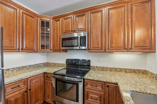 a kitchen with stainless steel appliances granite countertop white cabinets a stove and a microwave