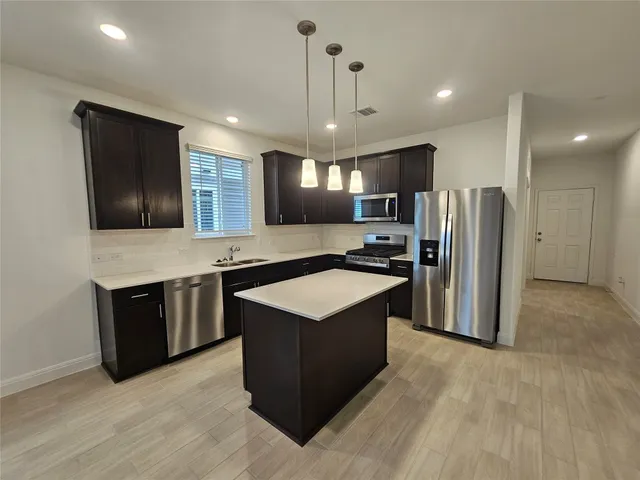 a kitchen with stainless steel appliances granite countertop a refrigerator a sink a stove and oven