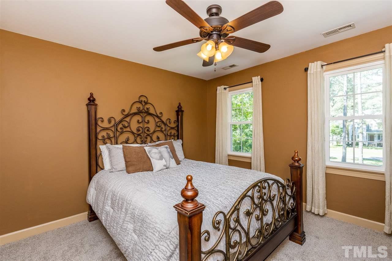 4504 Lassiter Road Wake Forest, NC 27587 - Photo 22 of 30 a bedroom with a large bed and a chandelier